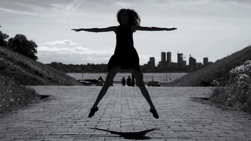 A dynamic black and white silhouette of a woman jumping with arms outstretched in Tallinn, Estonia.